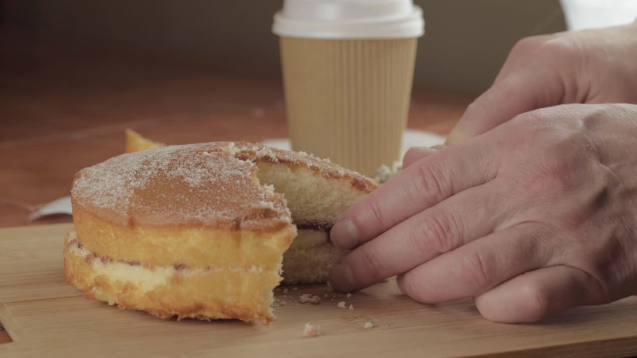 Slicking Victoria sponge cake with hot drink medium shot