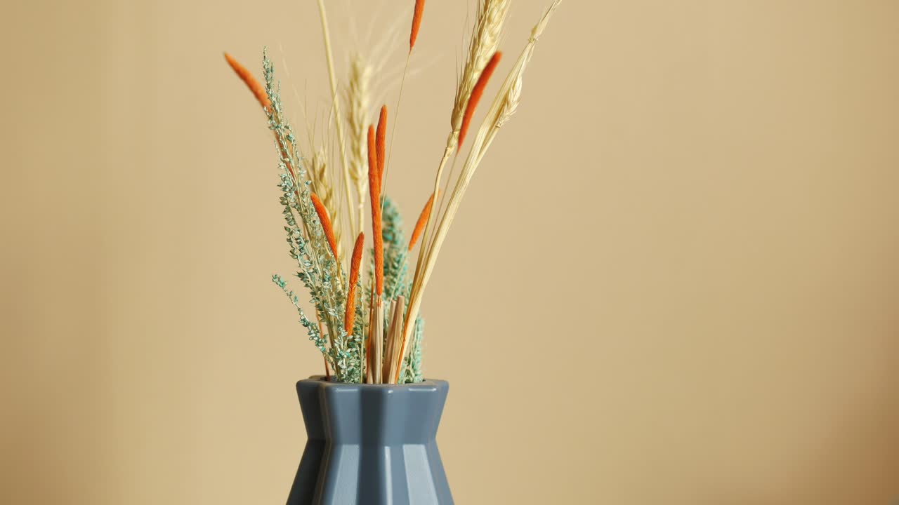 arreglo de flores secas en un jarrón azul