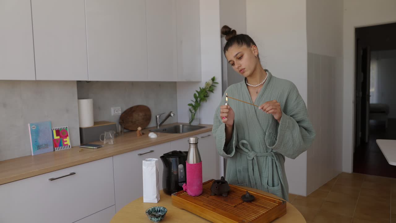 Woman lighting incense stick in kitchen