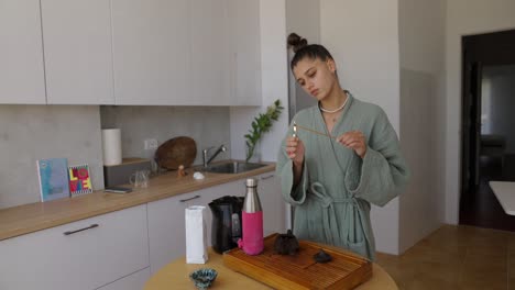 woman lighting incense stick in kitchen