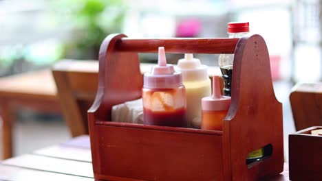 person placing a sauce bottle into a wooden basket.