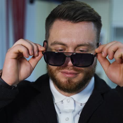 handsome man chooses fashion sunglasses in optics. wide assortment of modern eyewear in shop