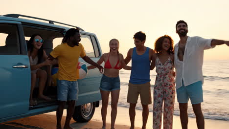 friends enjoying a beach sunset with a beach ball and van