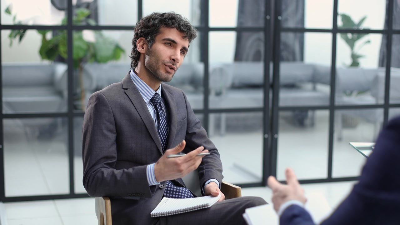 Young Businessman Talking and Taking Notes During an Interview