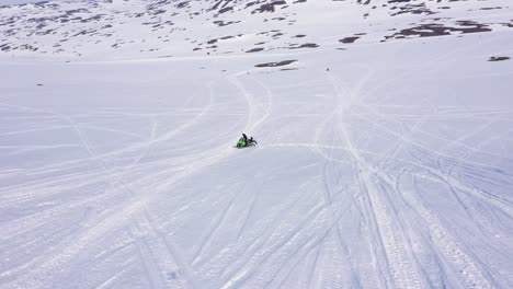 aerial view over snowy mountain landscape. snowmobile on the snow. sunny weather. circling clockwise.