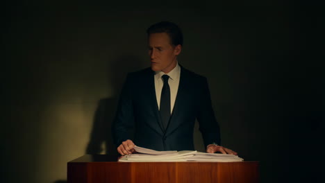 professional man in suit reading documents at a podium