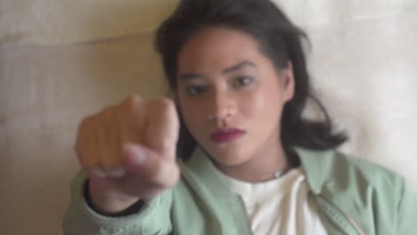 young woman lying on bed making a hand fist