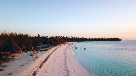 wonderful fly forwards drone shot over the coast line to a beach party