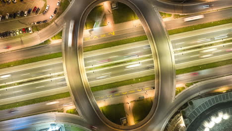 aerial view of a multi-level highway interchange at night with light trails