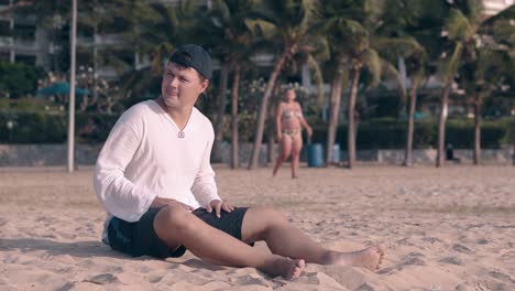 young man in casual clothes sits and talks on sea coast