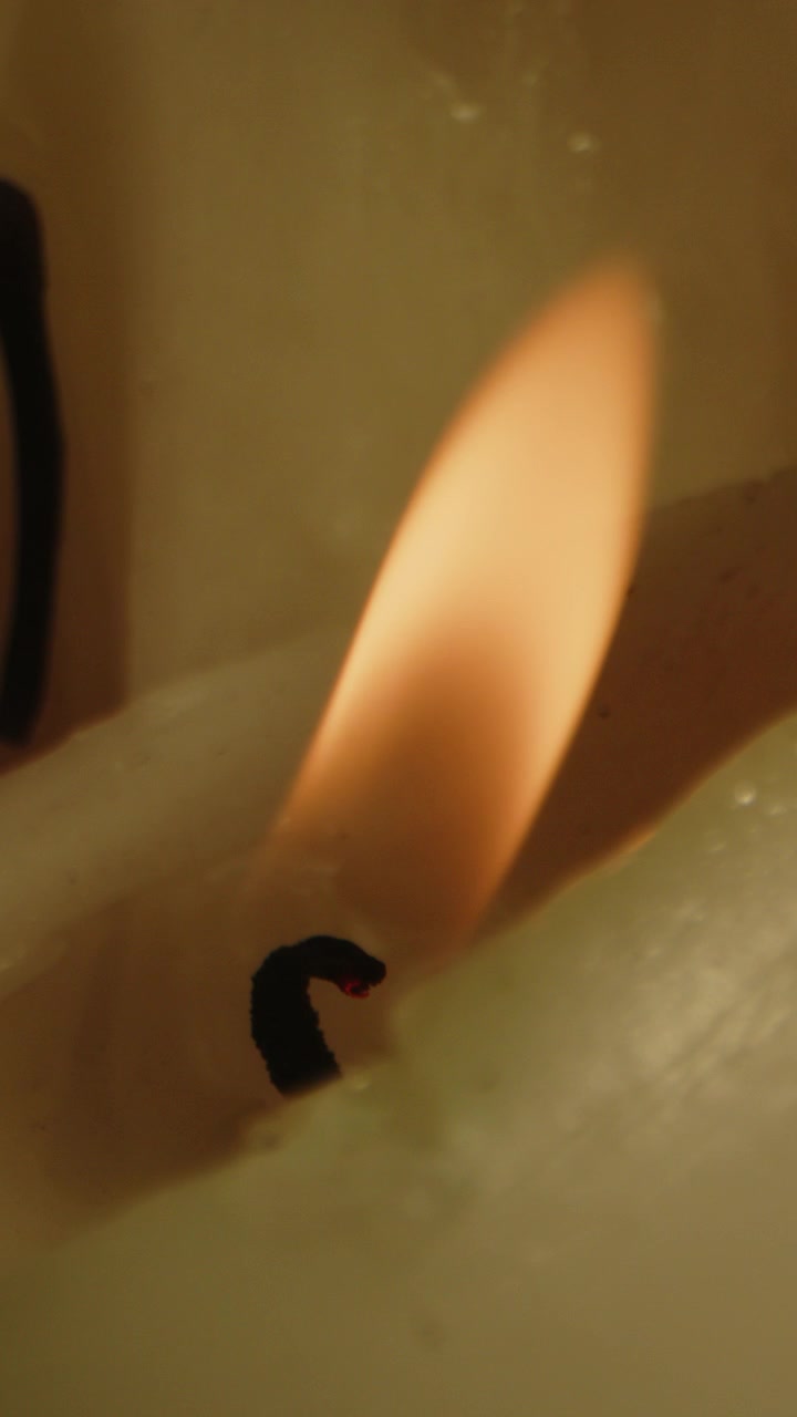 Vertical Beautiful macro of an burning candle and the orange fire being blown out in slow motion