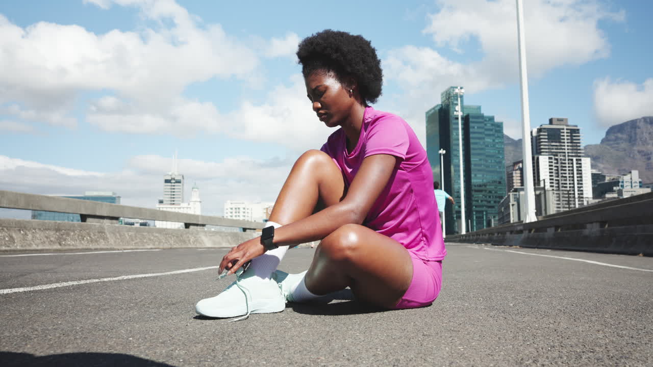 Young Woman Tying Shoelaces and Checking Smartwatch on Urban Road