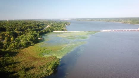 aerial view of upstream backwater of lock and dam 14 on mississippi river with dike, waterlilies, duckweed and trees along the shore