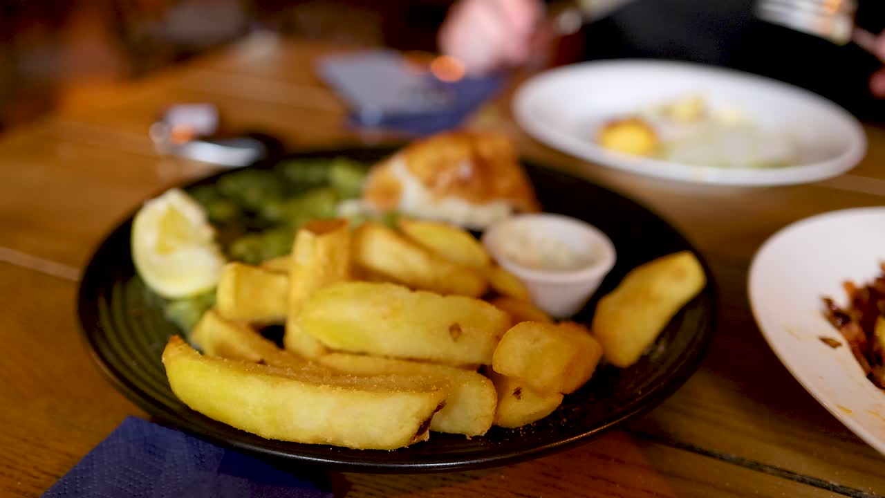 personas comiendo pescado y papas fritas en una mesa