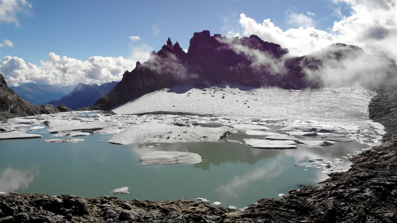 sobrevuelo aéreo hacia un glaciar al final de un lago lleno de icebergs derretidos en partes remotas de los alpes suizos en un día soleado