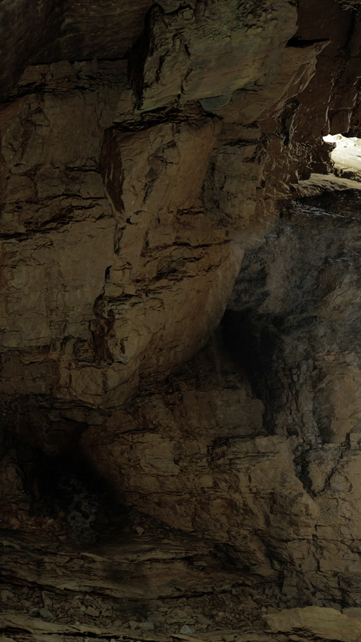 Exploration of a large cave with notable rock formations and shadows
