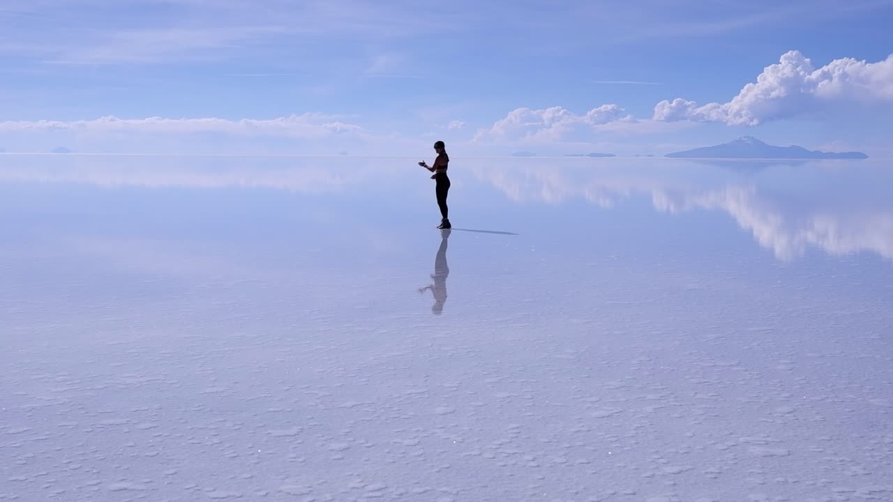 Woman on Uyuni Salt Flat lake reflected in shallow water, copy space