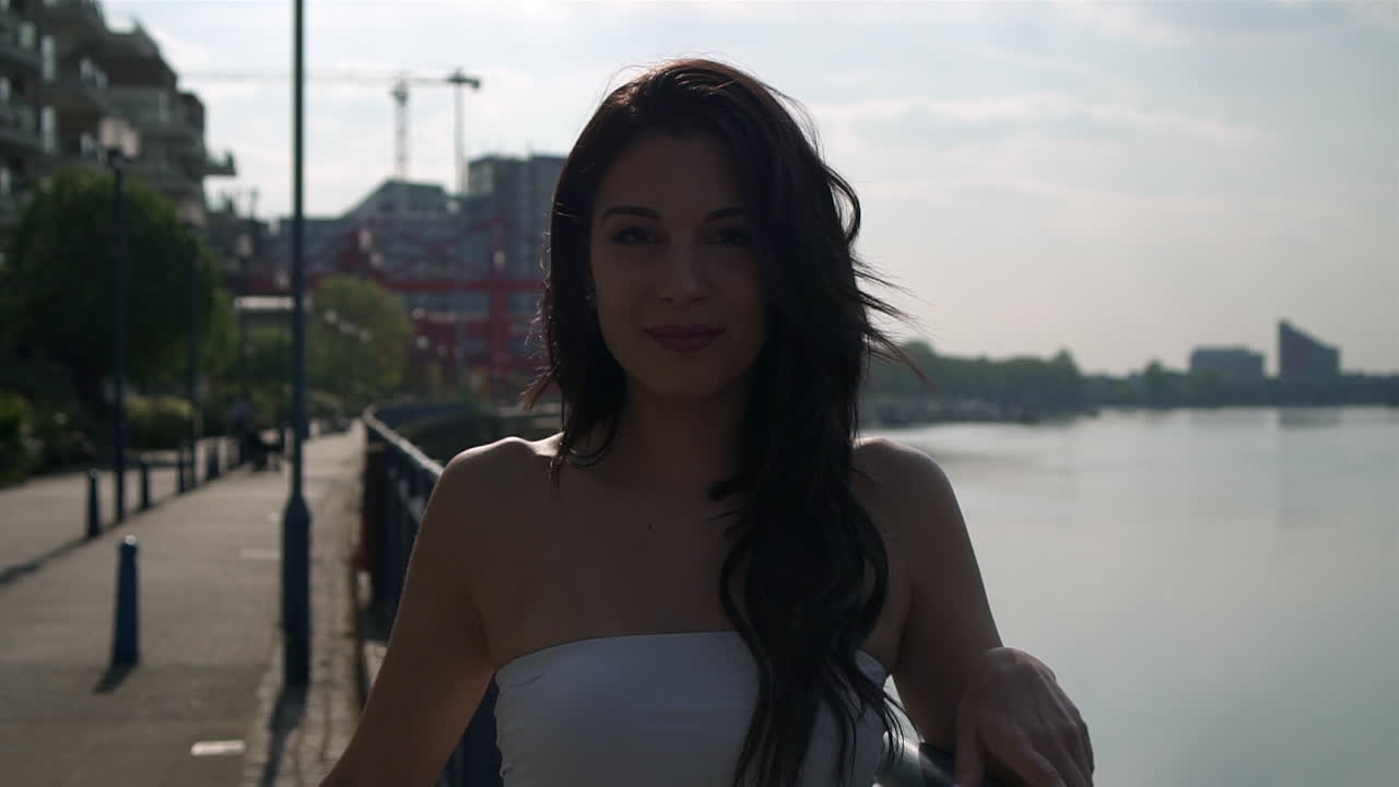 hermosa mujer latina de vacaciones girando y sonriendo a la cámara justo al lado del río támesis en londres