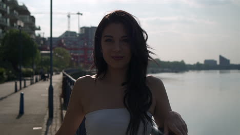 beautiful latina woman on holiday turning and smiling at the camera right next to the river thames in london