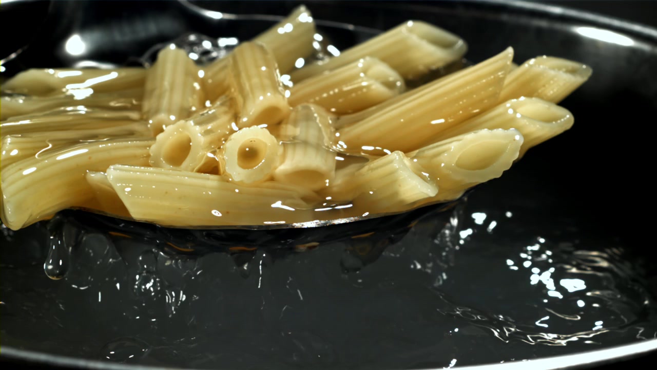 Penne cotte sollevate dall'acqua bollente al rallentatore