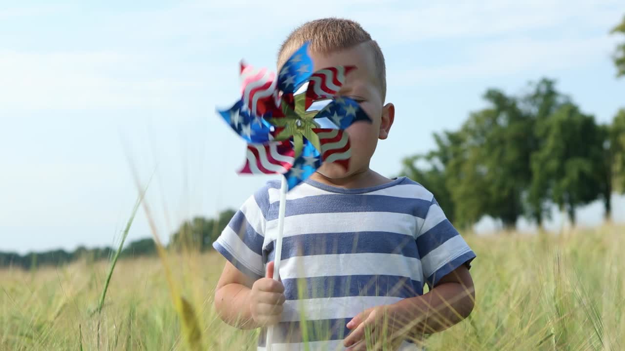 child boy kid playing with windmill pinwheel outdoors in green wheat field usa