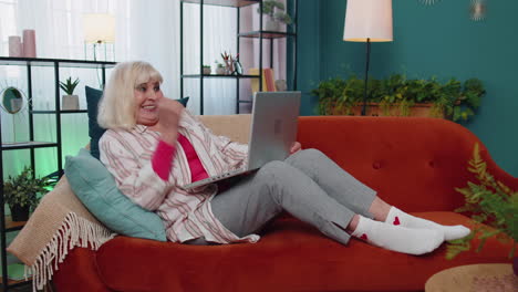 happy senior grandmother woman with laptop celebrate success win money in lottery online good news