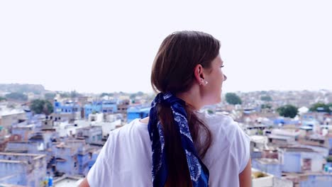 slow motion (120fps): young european female enjoys the view from the balcony above the blue city of jodhpur (india)