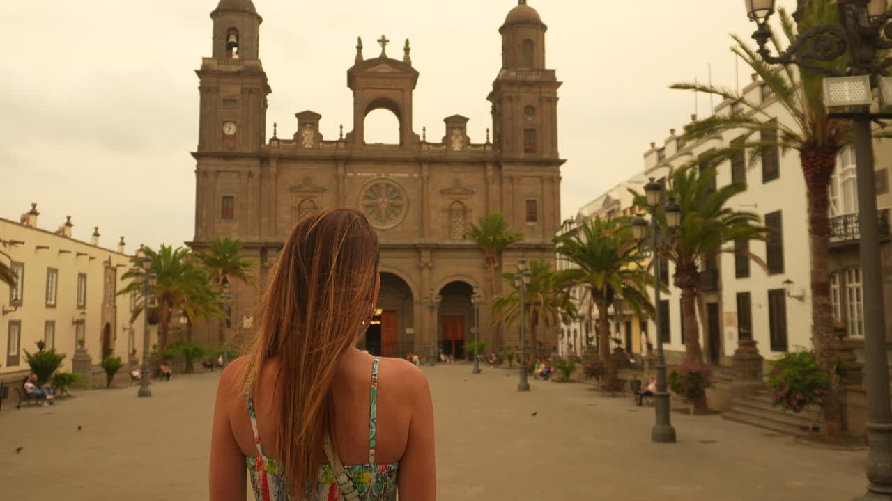 Tourist walking in Plaza de Santa Ana towards Las Palmas Cathedral in Gran Canaria