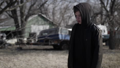 a young high school aged teen boy wearing a backpack walking down a road in slow motion a cold day