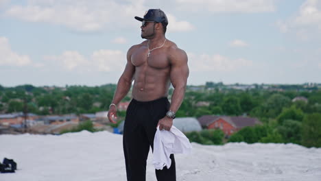 shirtless athlete with dark skin outdoors. muscular man standing on white hill in the countryside. handsome sportive african american guy without shirt looks aside.