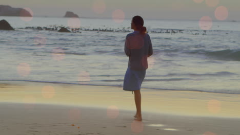 Animación-De-Puntos-De-Luz-Sobre-Una-Mujer-Birracial-Caminando-Por-La-Playa.