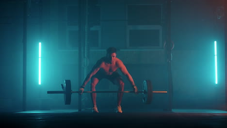 athletic shirtless man training doing power strength and endurance exercises with barbell. workout in the hardcore gym in slow motion
