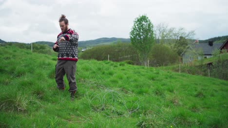 Man-Standing-On-Green-Field-Grass-With-Steel-Wire-For-Fencing