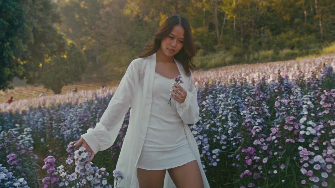 紫の花が咲く野原を歩く若い女性