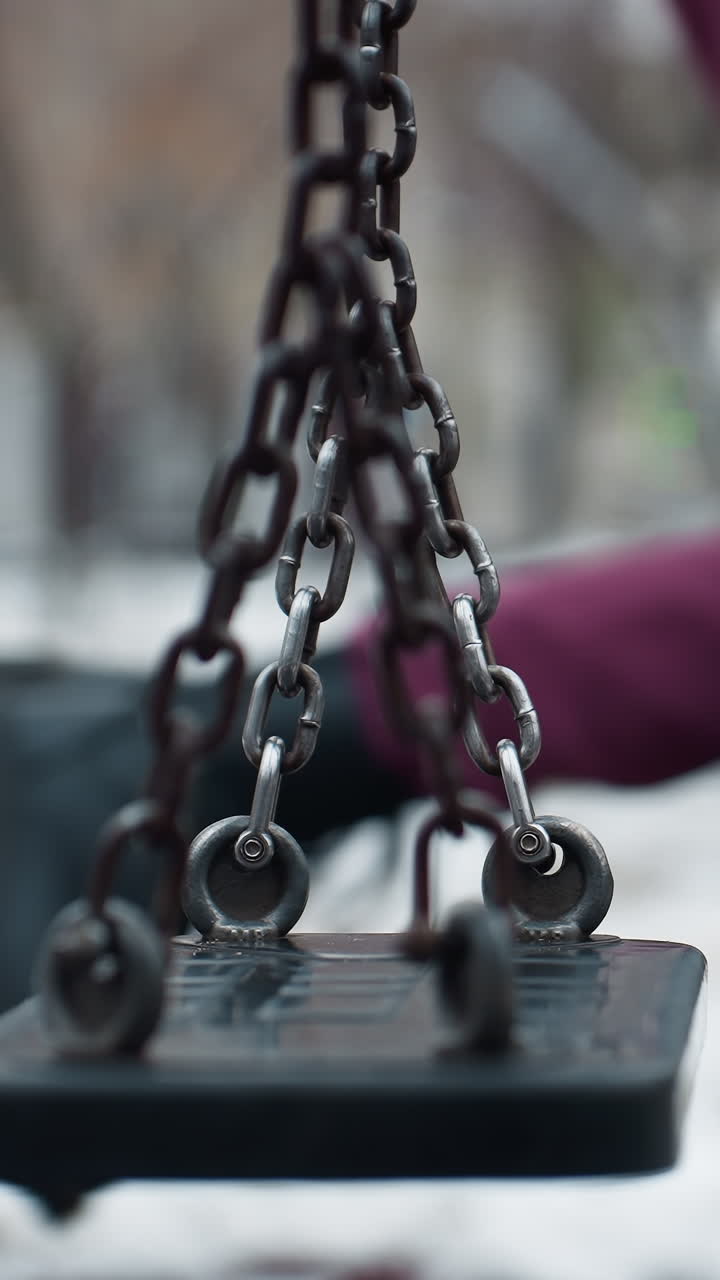 갈색 바지와 검은색 부츠를 입은 사람이 부드럽게 스에 흔들리는 부분적인 시각, 스 정적, 나무와 구조물의 흐릿한 배경으로 둘러싸인 눈