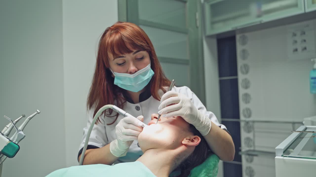 Dental clinic. Reception, examination of the patient. Teeth care. Dentist curing a girl patient