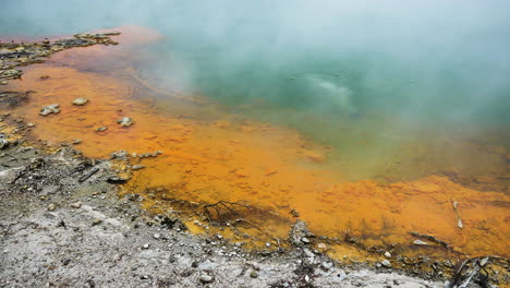 Close-up-of-hot-boiling-Champagner-Lake-with-Orpiment-and-stibnite-Mineral-in-yellow-orange-color-on-shore