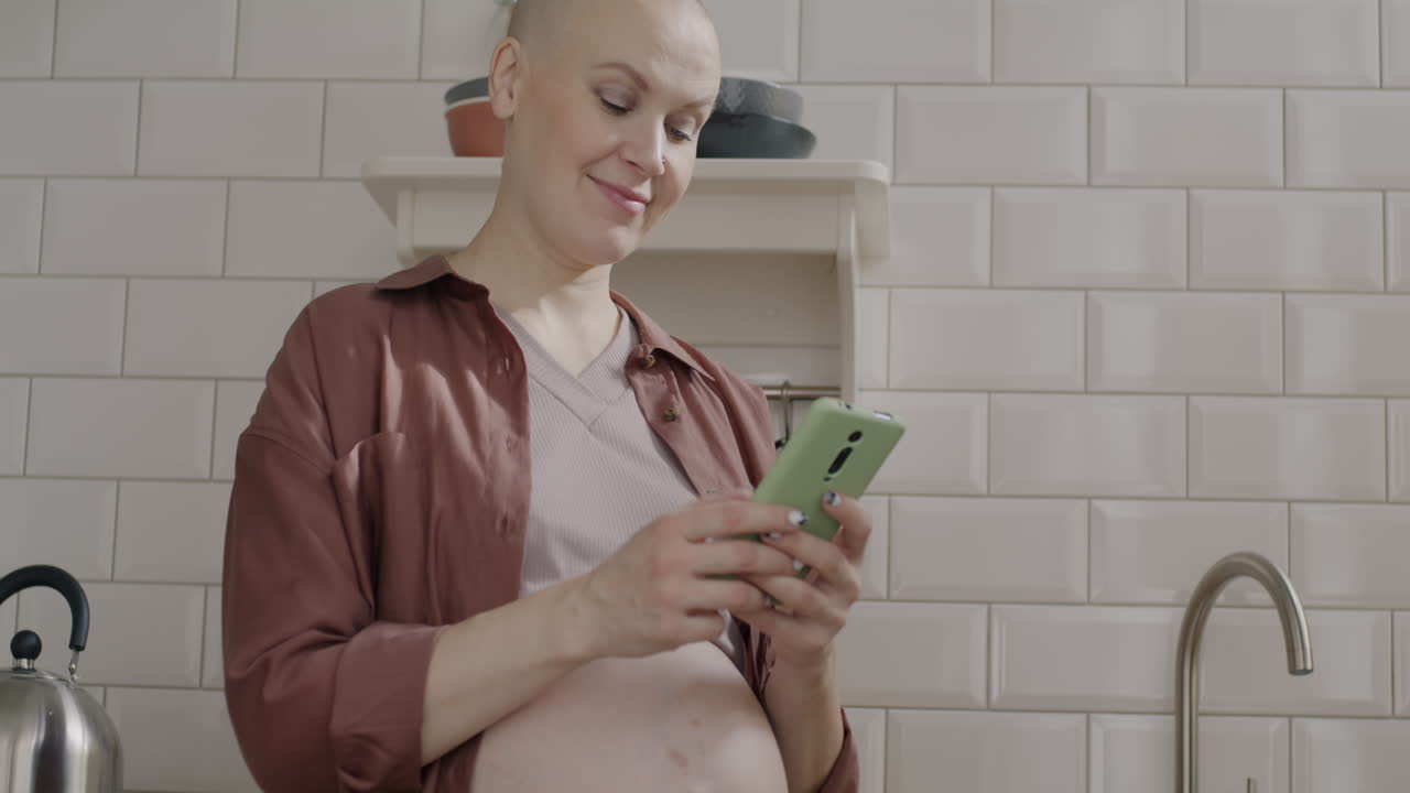 Pregnant woman using a phone in the kitchen