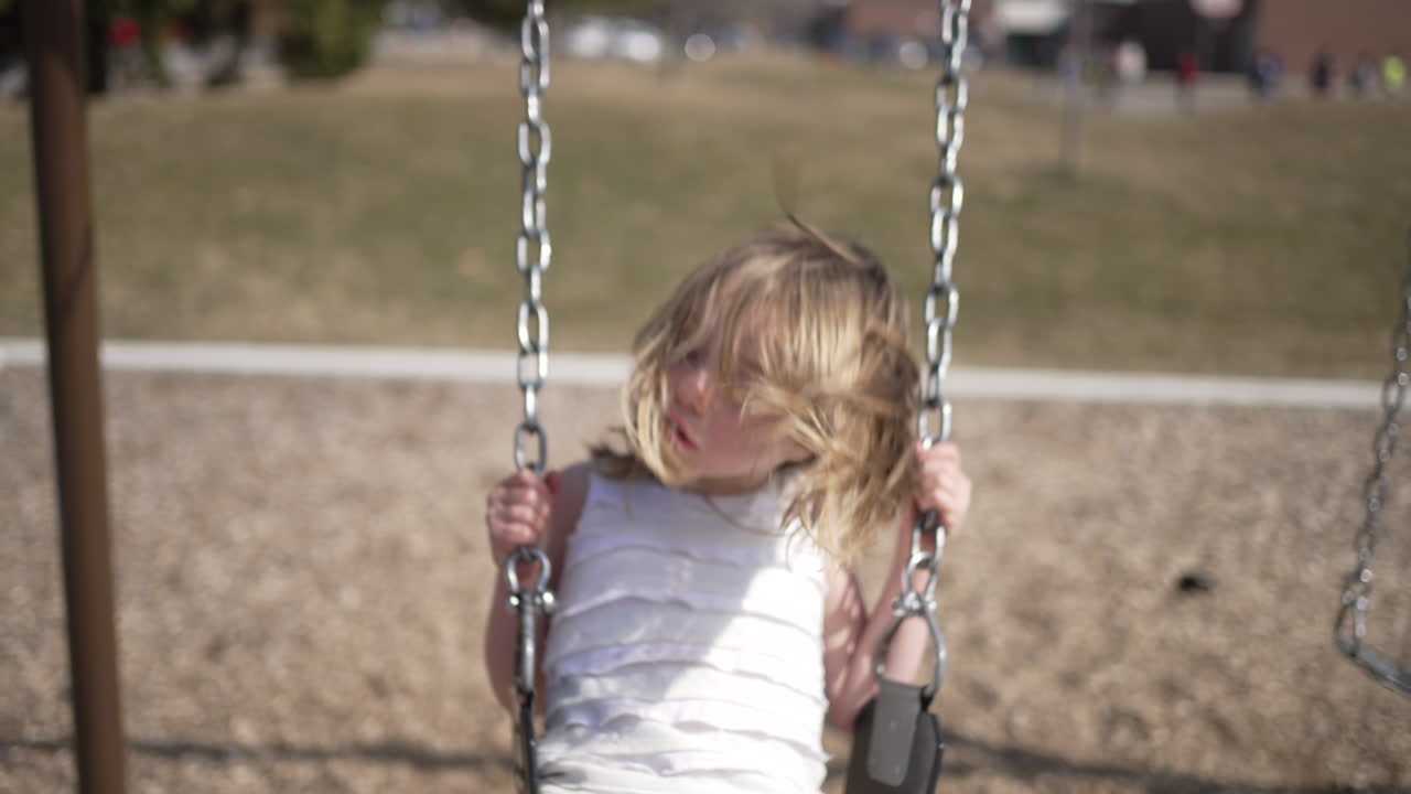 Bambina su un'altalena del parco giochi in slow motion