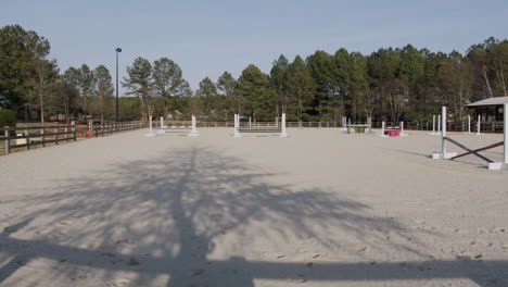 fenced area where horses are trained, with obstacles