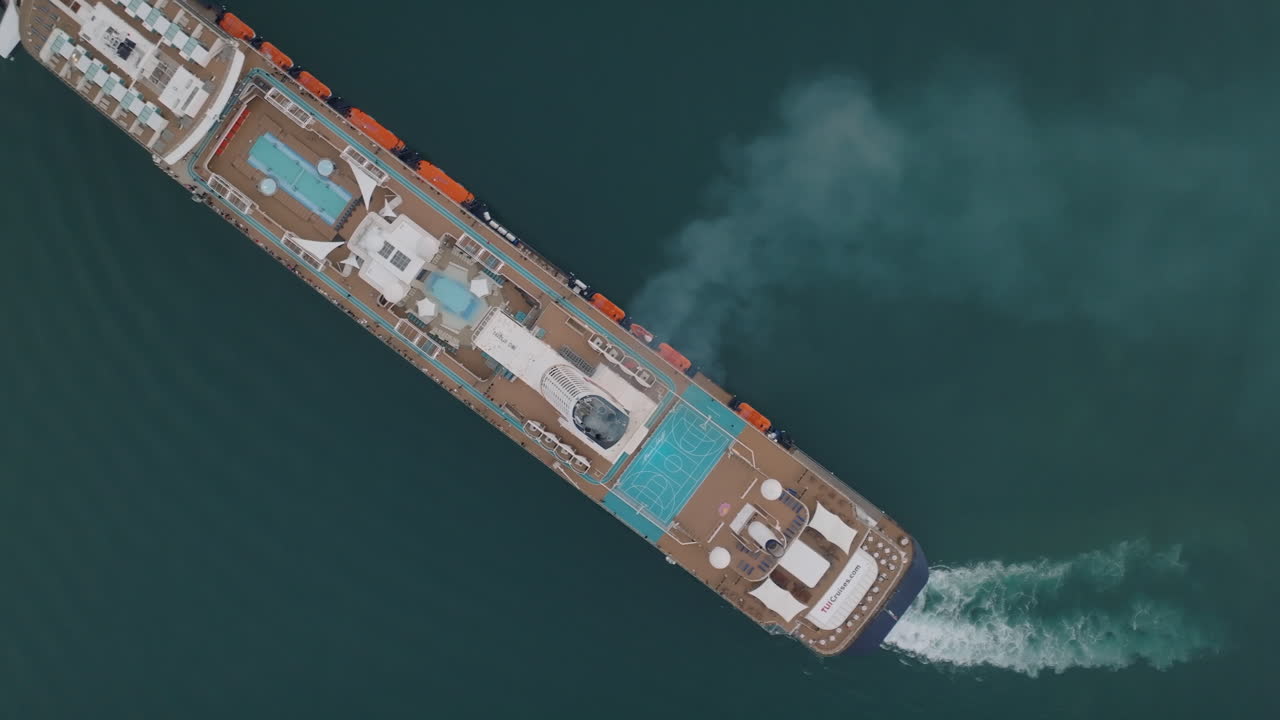 Smoke coming out of the funnel of a large cruise ship turning to starboard side