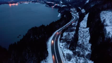 headlights glow along mountain road in front of distant town