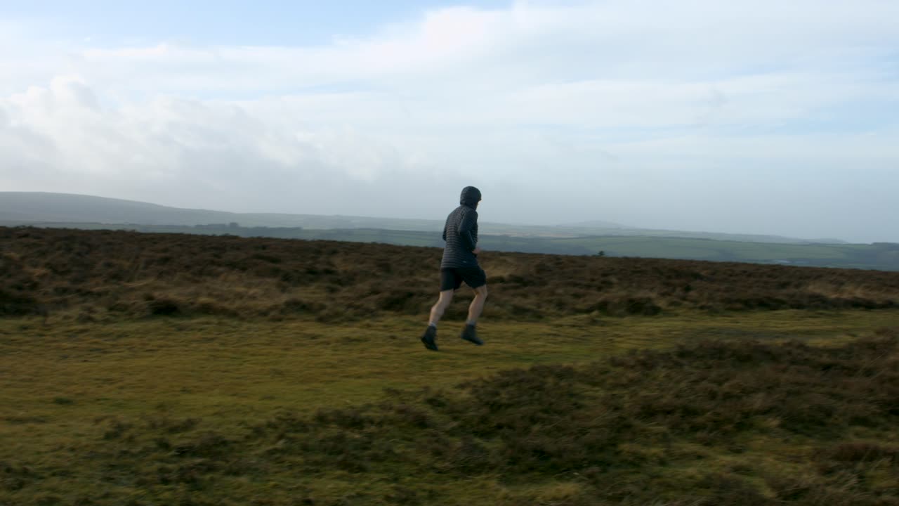 atleta de fitness masculino toma panorámica del corredor corriendo y entrenando en el campo de páramos exmoor uk 4k