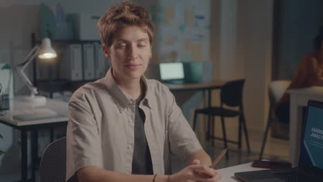 young woman posing on camera at office workplace during night