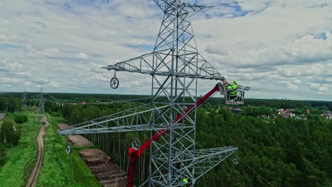 Men-In-An-Elevated-Crane-Basket-Working-On-Cables-Of-High-Voltage-Transmission-Tower