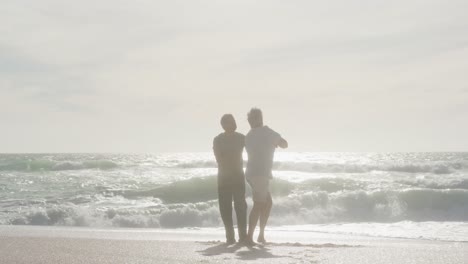 feliz pareja de graduados hispanos bailando en la playa al atardecer