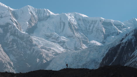 Drone-shot-of-a-male-hikes-over-the-ridge-alongside-Mount-Everest-Nepal-shining-snow-and-sunlight,-Adventurous-life-time-experience-landscape,-peaceful,-calm-4K