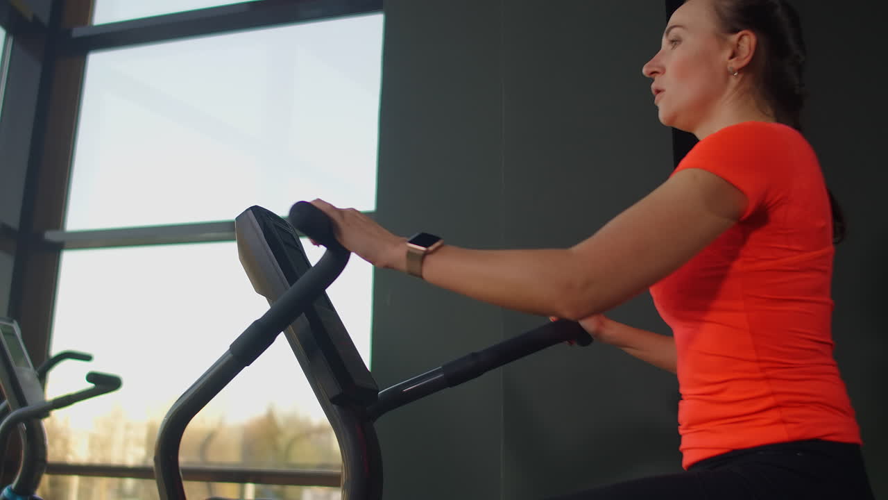 mujer joven activa girando una bicicleta de aire en el gimnasio con entrenadores. entrenamiento femenino en bicicleta de aire