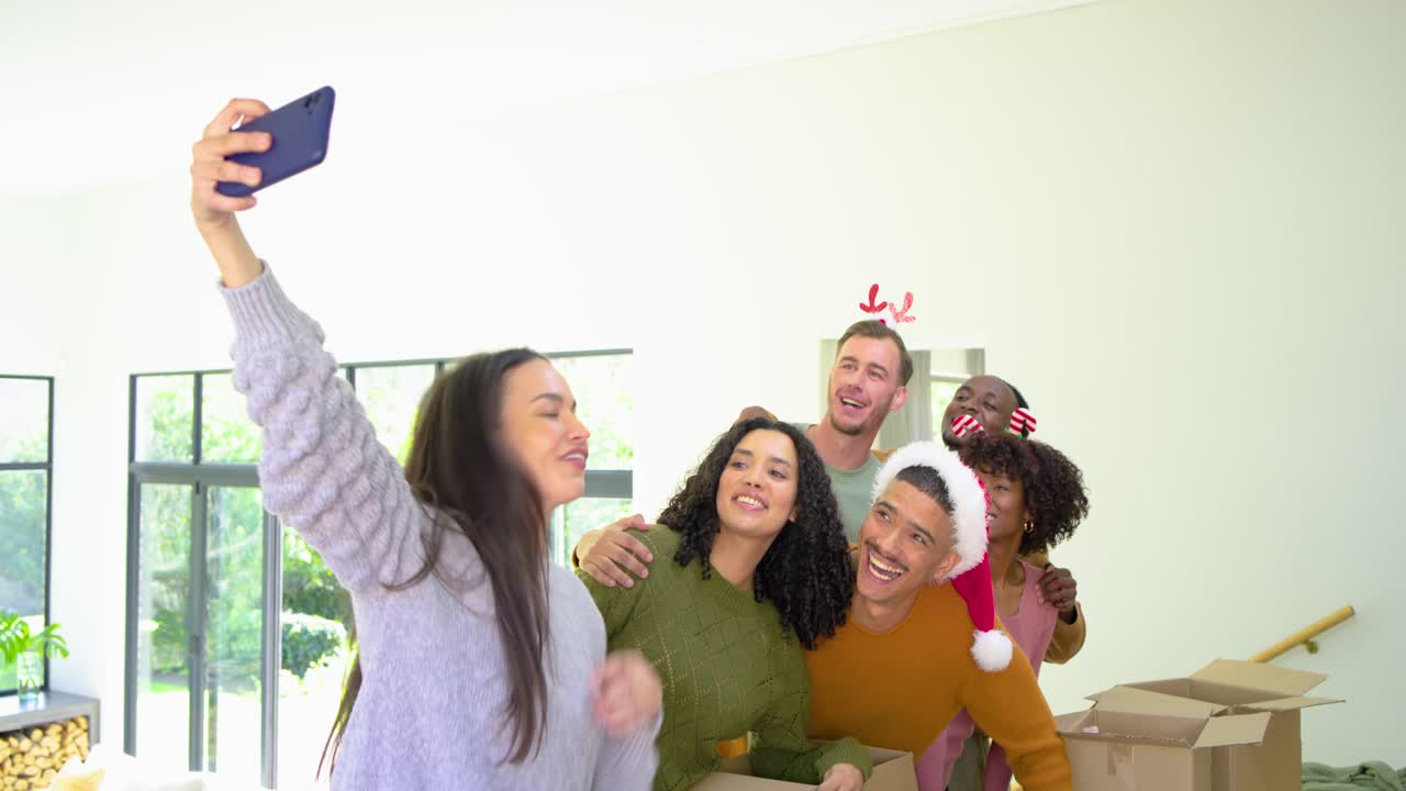 Diverse friends sorting clothes leading filling Donation boxes at home, taking phone selfie