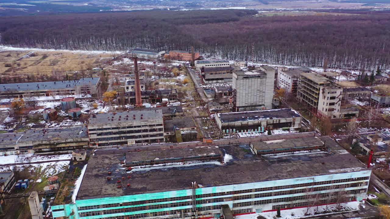 Empty broken industrial plant. Old factory near the forest. Flight over the ruined place after the military actions. Aerial view.
